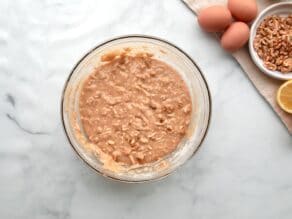 Horizontal overhead shot of a glass mixing bowl containing mixed mandel bread ingredients.