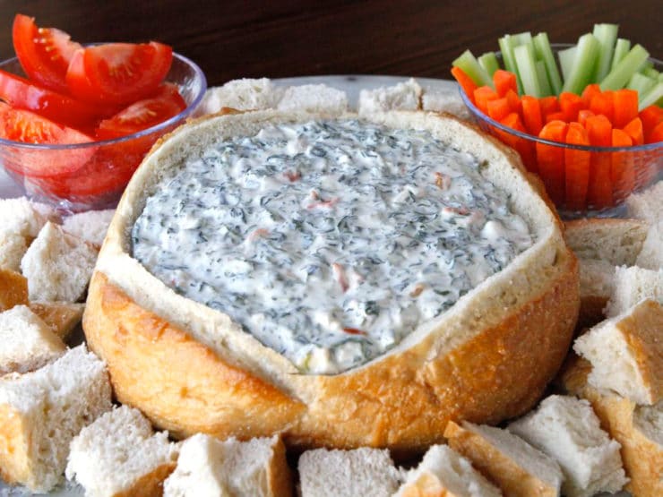 A bowl of Spinach Dip surrounded by bread and vegetables, ready to be enjoyed as a delicious appetizer