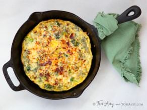 Broccoli Cheddar Frittata with Smoked Paprika on a skillet with a green clothe wrapped on the skillet's handle