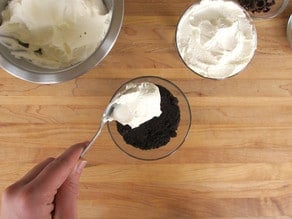 Topping parfait cups with whipped cream.