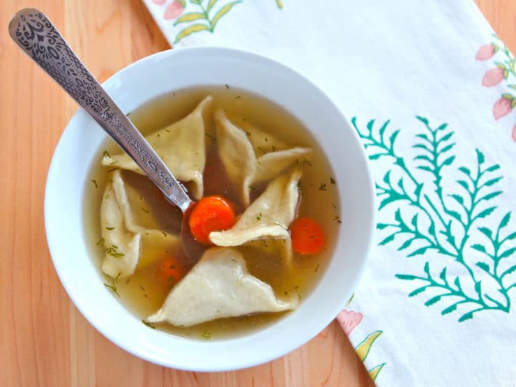 A bowl of chicken soup with dumplings and carrots