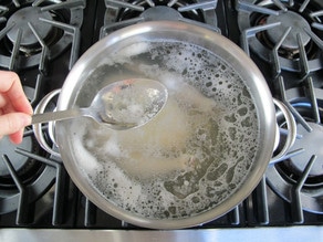 Whole chicken boiling in a stockpot.