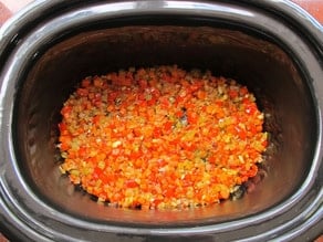 Sauteed vegetables added to the bottom of a slow cooker.