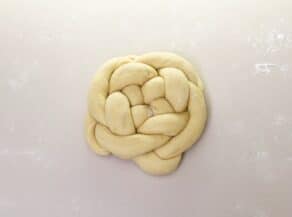 Overhead shot of challah dough braided into a circular loaf.