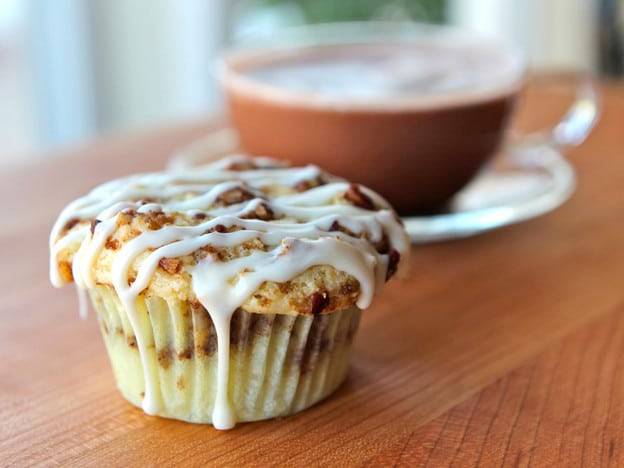 A Coffee Cake Cupcake with icing on top is placed on a wooden table.