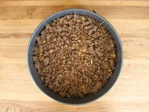 Streusel sprinkled over batter in a round cake pan.