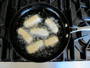 Frying fish pieces in a skillet.