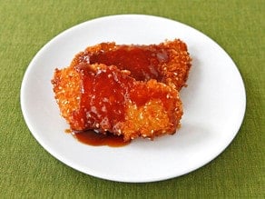 A delicious Crispy Panko Fish with Orange Sesame Sauce served on a white plate with fork on side