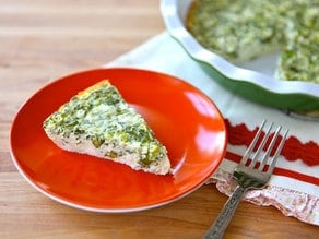 A plate with a crustless quiche featuring spinach, cheese, feta, and asparagus