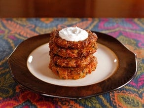 Horizontal image of four layers of Curry Latkes on an elegant plate.