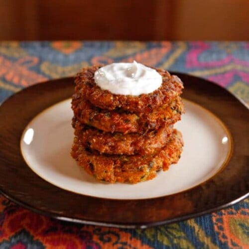 Horizontal image of four layers of Curry Latkes on an elegant plate.