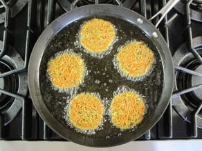 Latkes frying in a skillet.