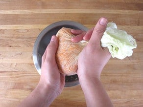 Squeezing water out of shredded carrots in cheesecloth.