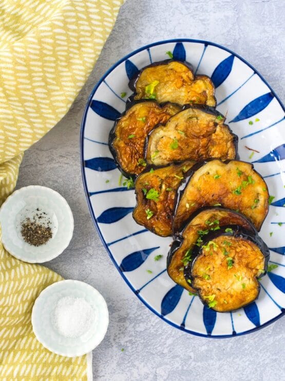 Fried eggplant on plate with salt and pepper.