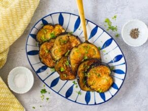 Plate of fried eggplant cooked golden crisp on marble background - overhead shot