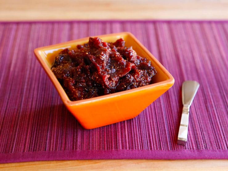 Fig Preserves on a small orange square-shaped bowl with a silver butter spreader knife