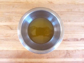 Combining ingredients for ginger beer in stainless steel bowl on cutting board.