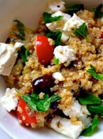 Greek Infused Quinoa Salad with tomatoes, fresh oregano, olives, and quinoa served on a white bowl