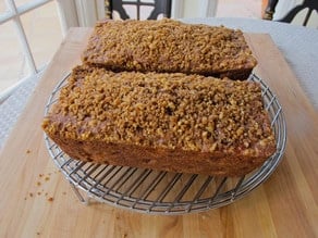 Two loaf cakes cooling on a rack.