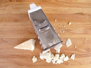 Shaving parmesan on a cutting board.