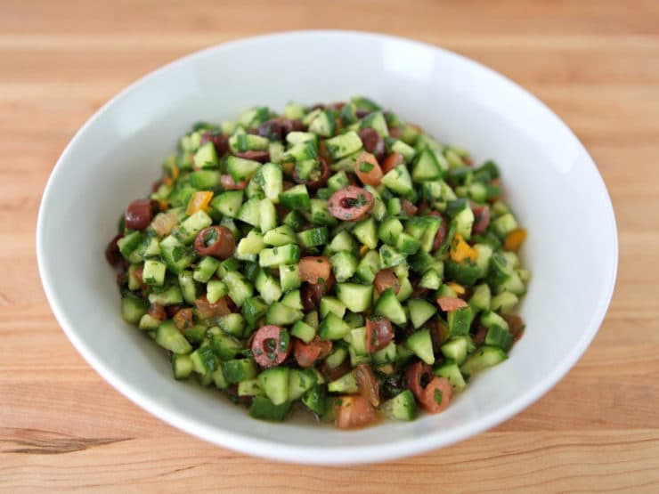 Fresh Israeli salad with diced tomatoes, cucumbers, onions, and parsley, drizzled with olive oil and lemon juice