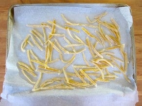 Sugared lemon peels drying on parchment.