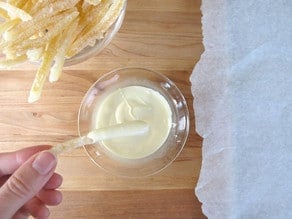 Dipping lemon peels in white chocolate.