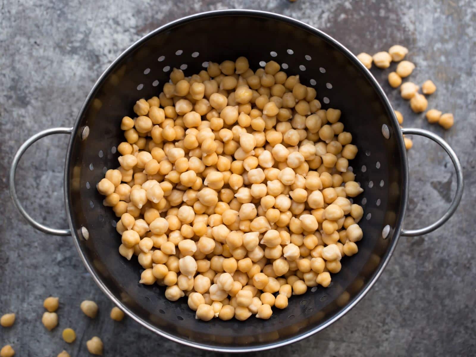 A colander filled with chickpeas on a table