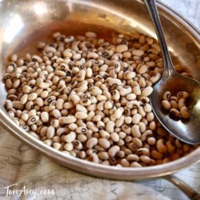 Dried black eyed peas in metal bowl with spoon.