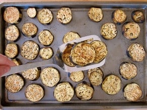 Removing roasted eggplant from baking sheet.