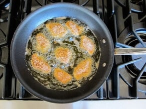 Frying chicken bites in a skillet.