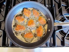 Frying chicken bites in a skillet.