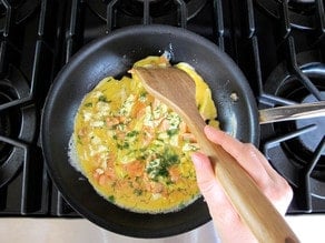 Scrambling eggs in a skillet.