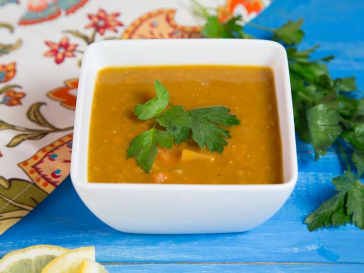 A bowl of smoky lentil sweet potato soup, garnished with fresh herbs