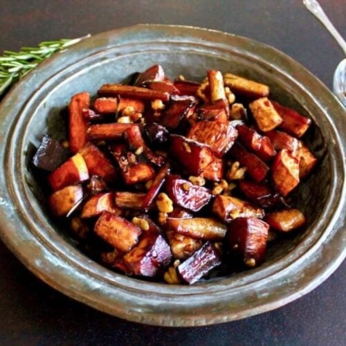 Rustic plate of Roasted Rosemary Balsamic Tzimmes, rosemary sprigs in background.