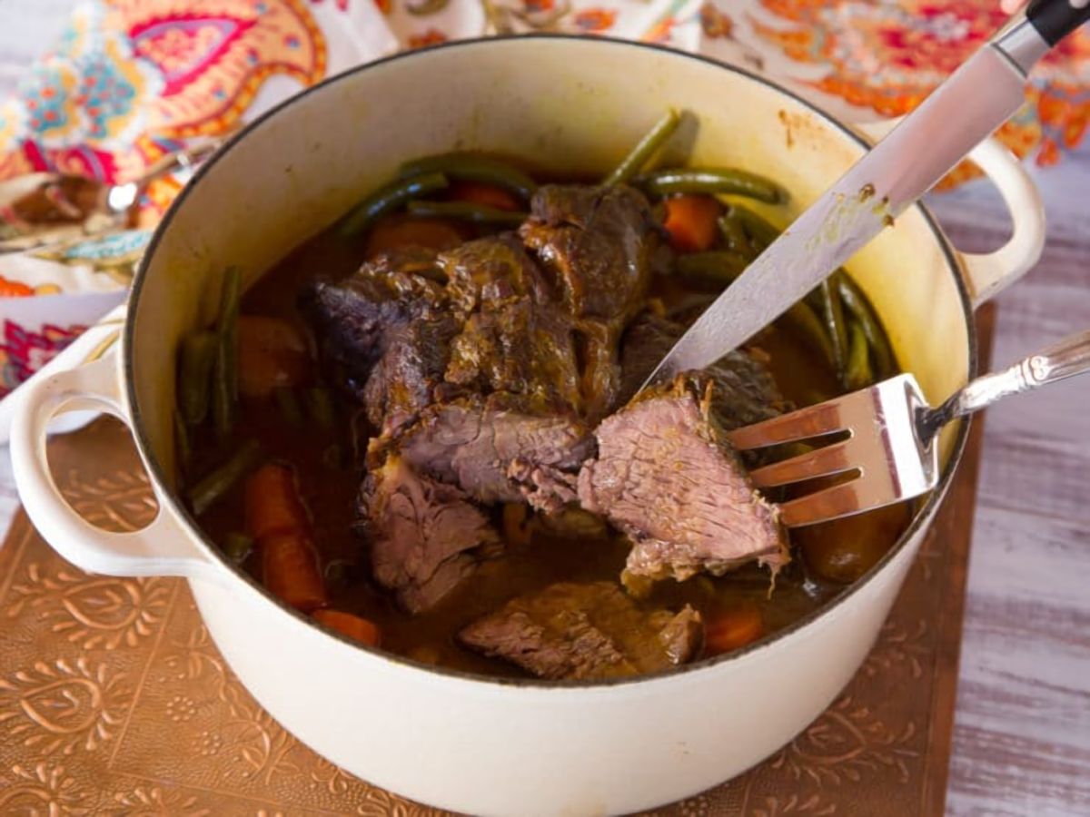 A savory grass-fed pot roast with meat, vegetables, and a fork on the side