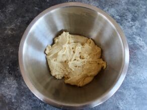 Soft sticky dough at bottom of mixing bowl on concrete surface.