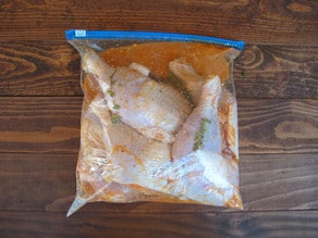 Chicken pieces marinating in a bag.