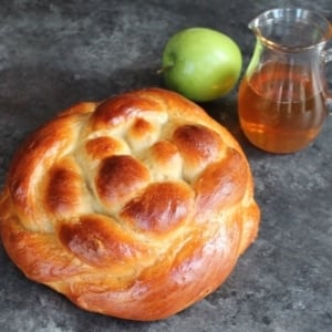 Freshly baked bread on a countertop with a Picher of honey and green apple