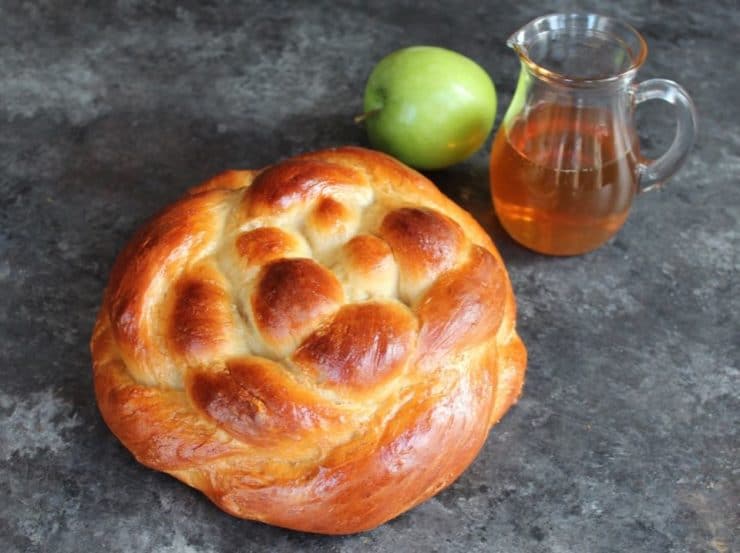 Freshly baked bread on a countertop with a Picher of honey and green apple