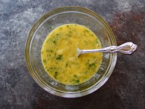 Beaten eggs in a glass mixing bowl with a fork.