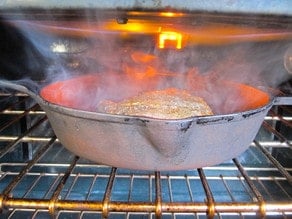 Steak in cast iron pan under broiler.