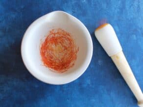 Saffron in mortar and pestle, pulverized into powder.