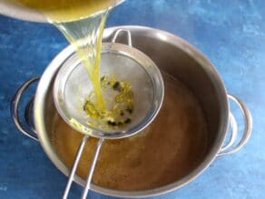 Straining chicken stock through a wire mesh strainer.