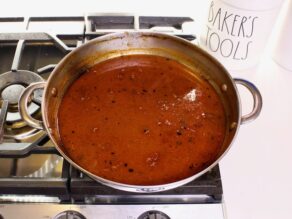 Pan with red sauce and brown bits reduced on stovetop.