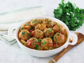 Horizontal image of a white bowl filled with "unstuffed cabbage". A bunch of fresh parsley sits in the back left corner.