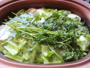 Slow cooker filled with chicken stock ingredients and water ready to cook.