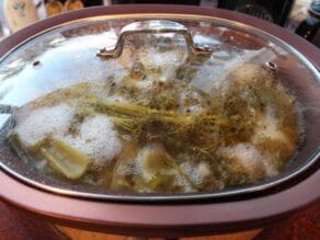 Chicken stock cooking in slow cooker with lid on.