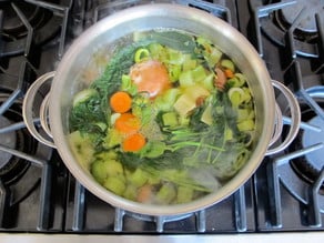 Diced vegetables covered with water in a stockpot.