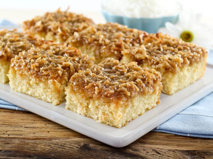 A plate full of square daisy flower cake slices, accompanied by a daisy flower in the background